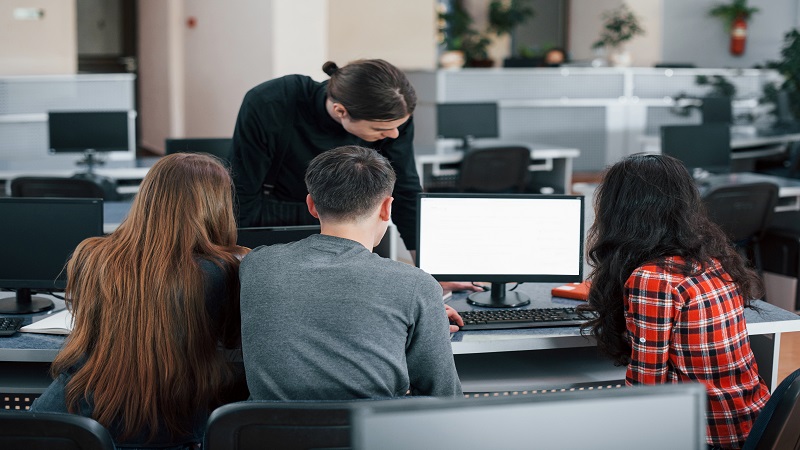 Screen with white color. Put your text there. Group of young people in casual clothes working in the modern office.